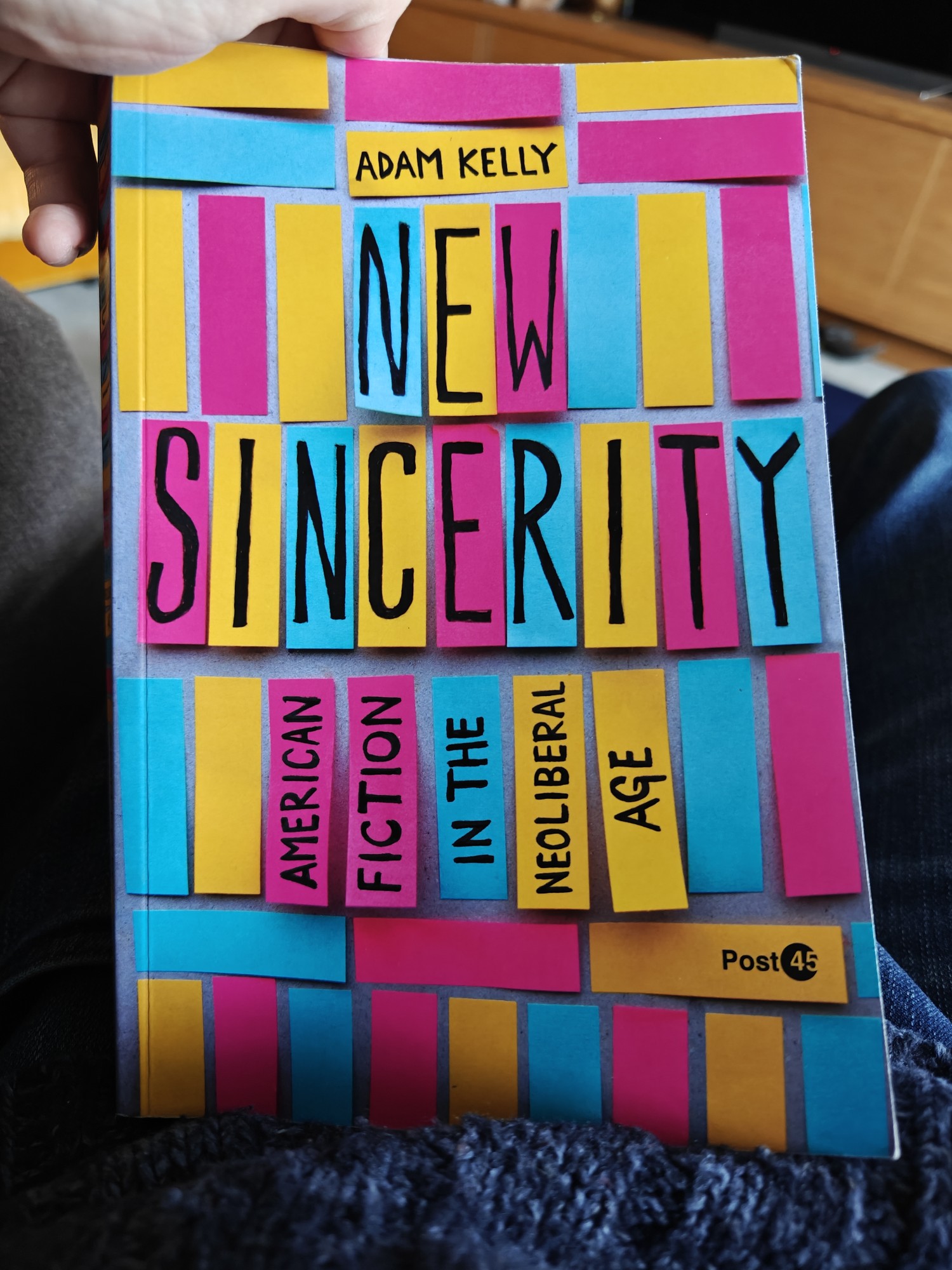 A picture of the cover for Adam Kelly's New Sincerity: American Fiction in the Neoliberal Age. It contains a range of yellow, pink, and blue rectangles arranged in a patchwork, like post it notes, with the title in the rectangles. 