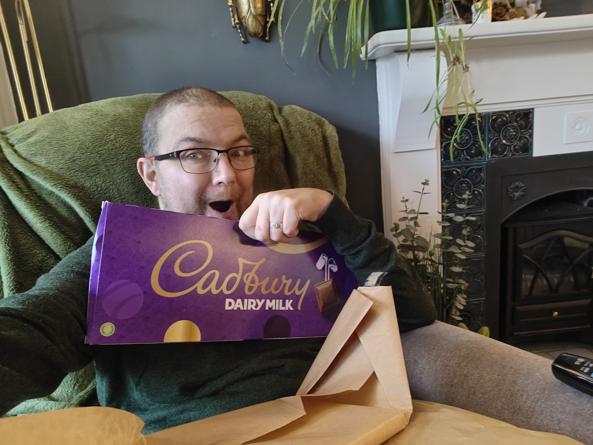 Me holding a massive bar of chocolate - Cadbury Dairy Milk - wearing a green jumper and pulling an odd face 