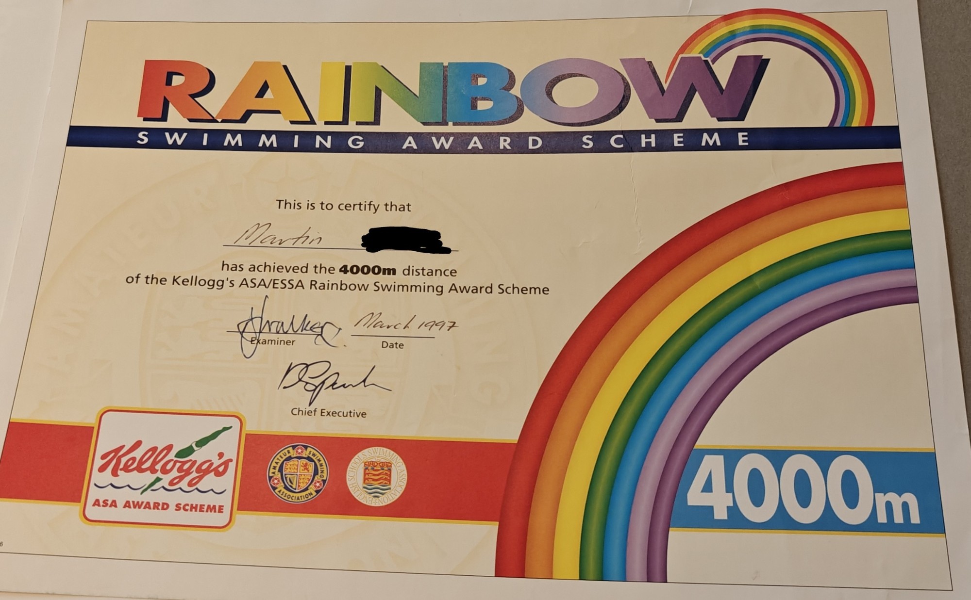A rainbow swimming certificate saying 4000 metres. The certificate features a rainbow and the text "Rainbow Swimming Award Scheme" at the top. 