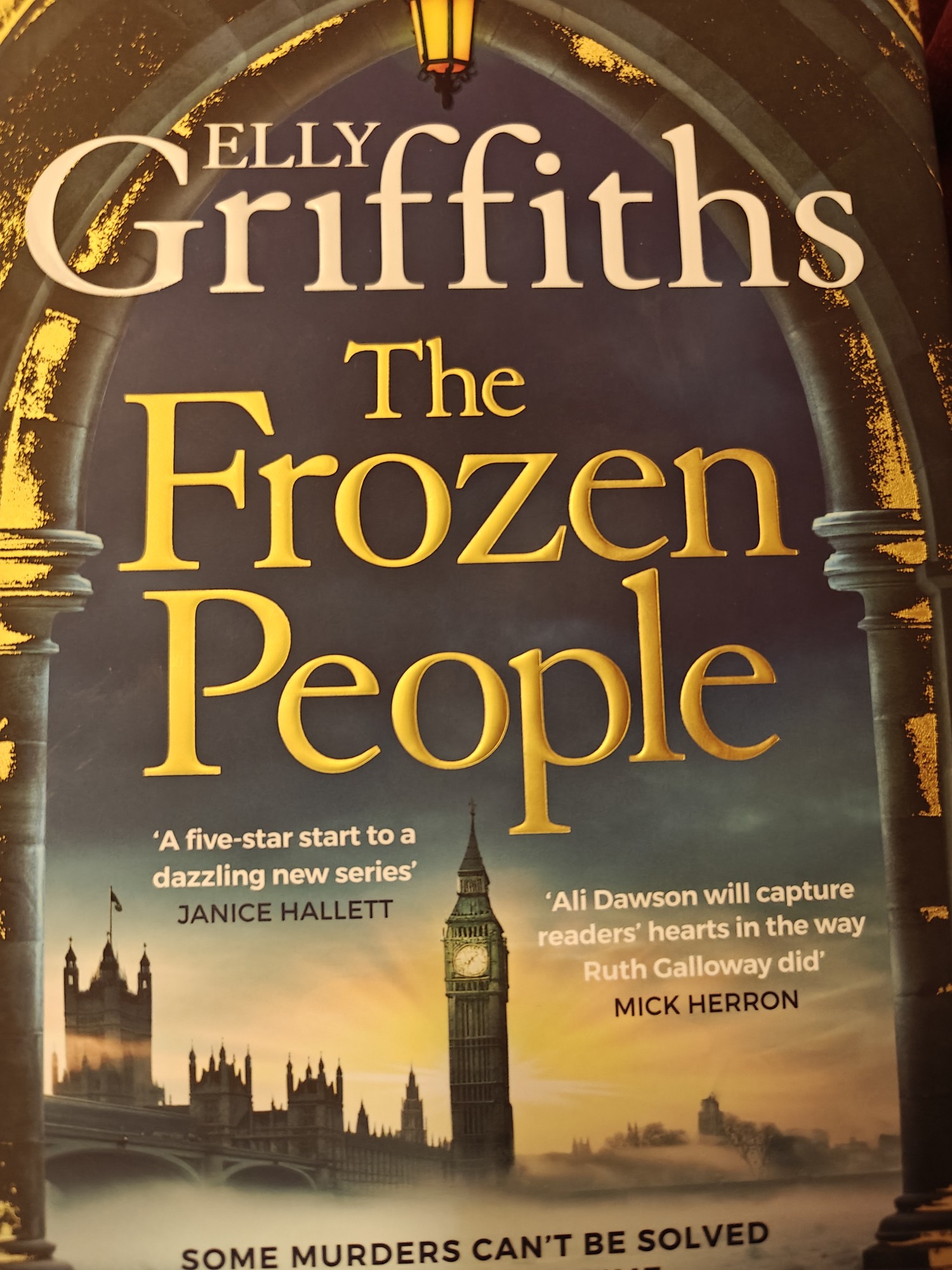 The cover of The Frozen People by Elly Griffith with the title text above a foggy London landscape with Big Ben visible. The text blurb at the bottom says "Some murders can't be solved in a lifetime" 