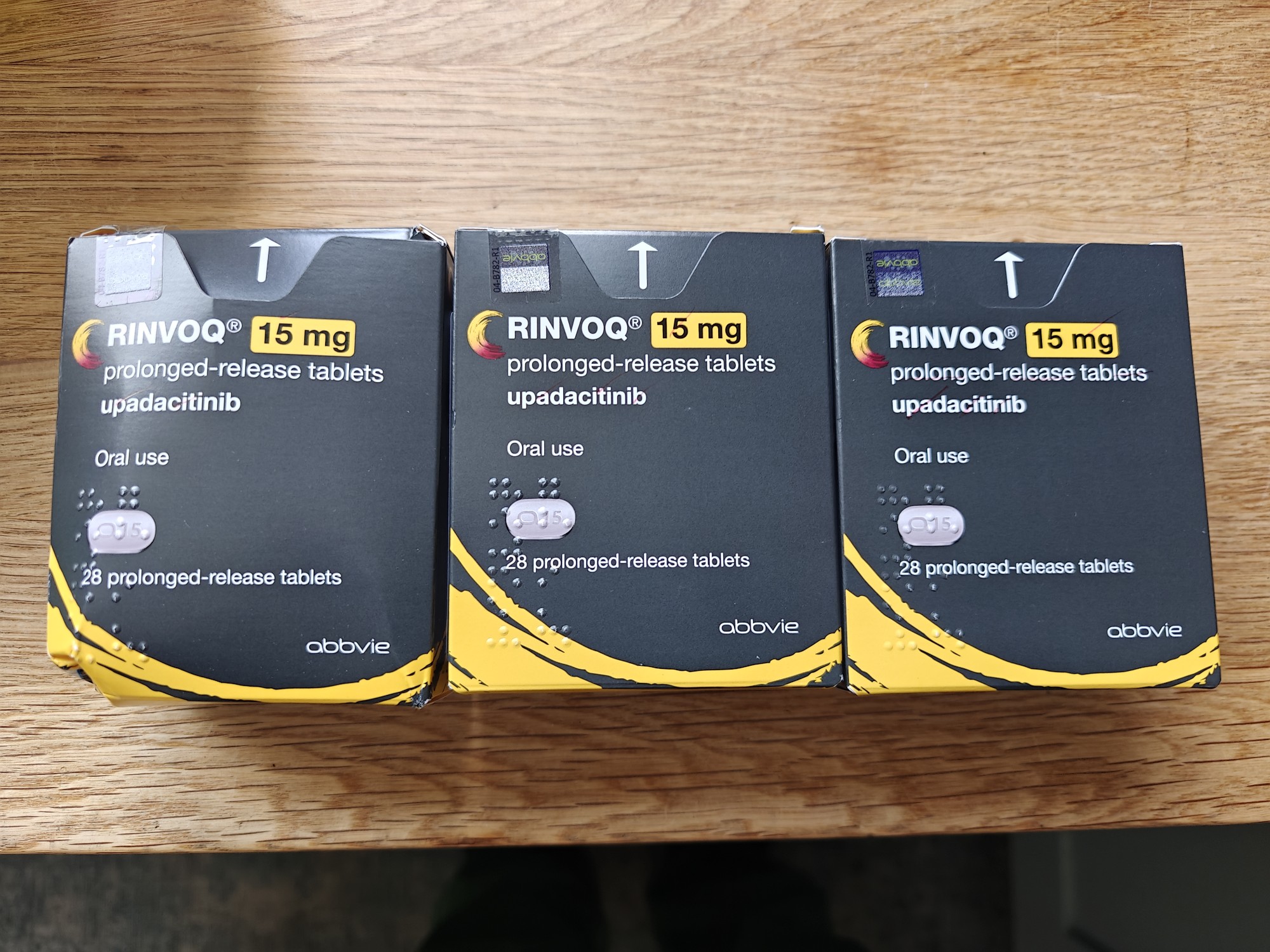 Pictures of the drug Rinvoq (Upadacitinib) in its packaging, which is yellow and black. 
