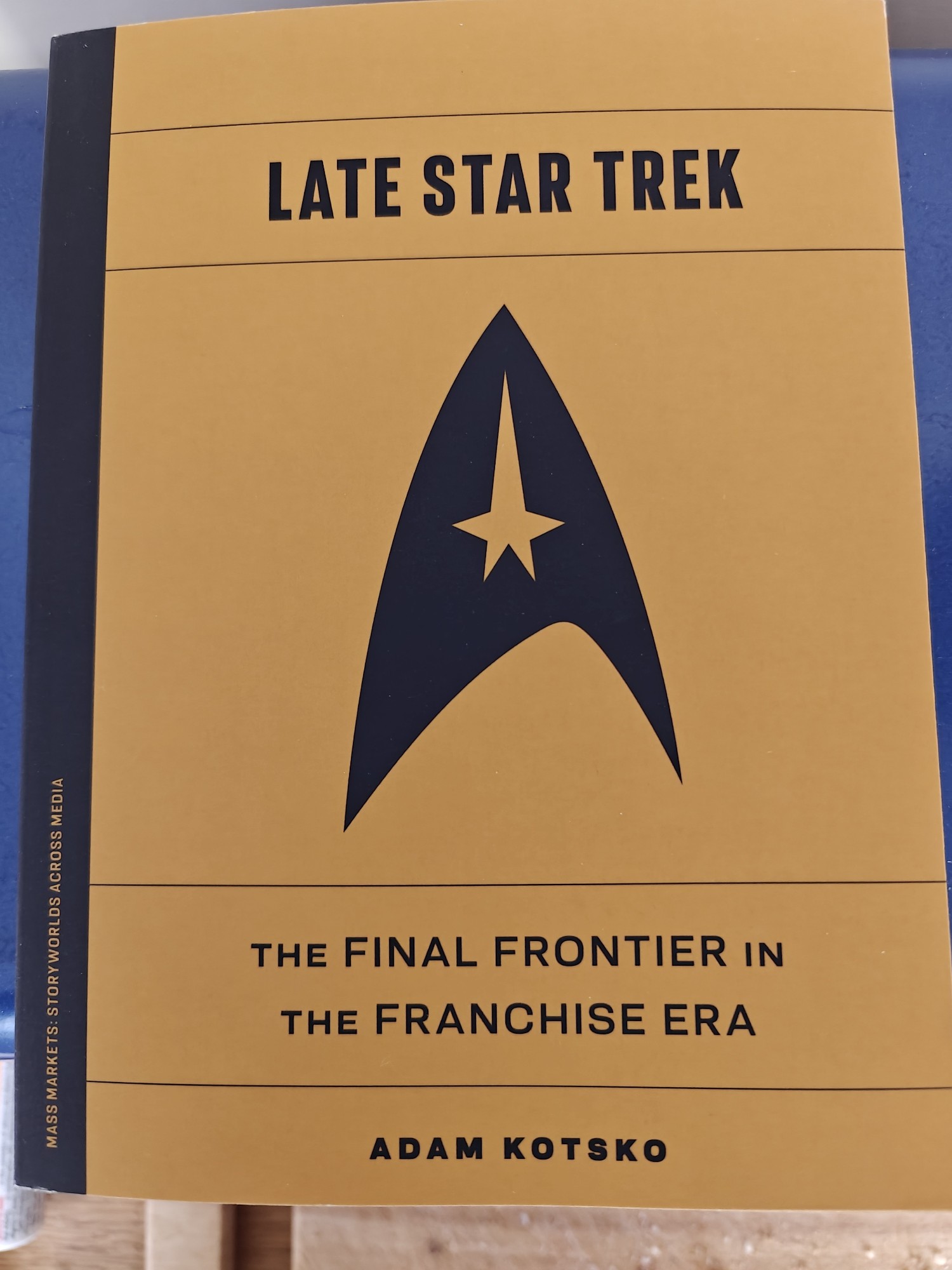 The cover of Late Star Trek by Adam Kotsko. It depicts a Star Trek communicator on an amber background. The subtitle is "The Final Frontier in the Franchise Era".