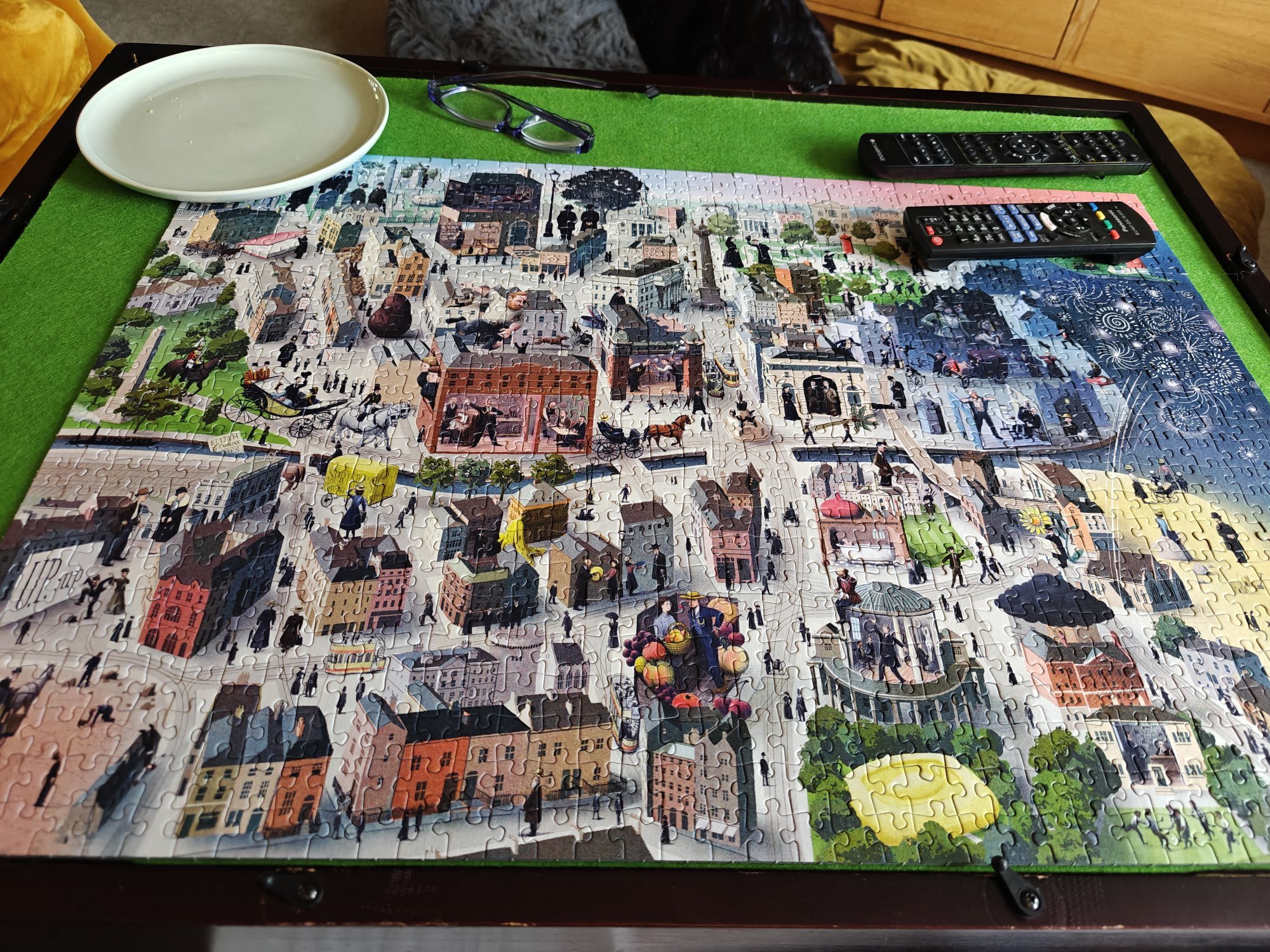 A picture of the jigsaw, which depicts a town, with a grassy area at the bottom right. There is too much complexity to capture here, but suffice it to say that there are significant liner notes that explain each part of the puzzle. 