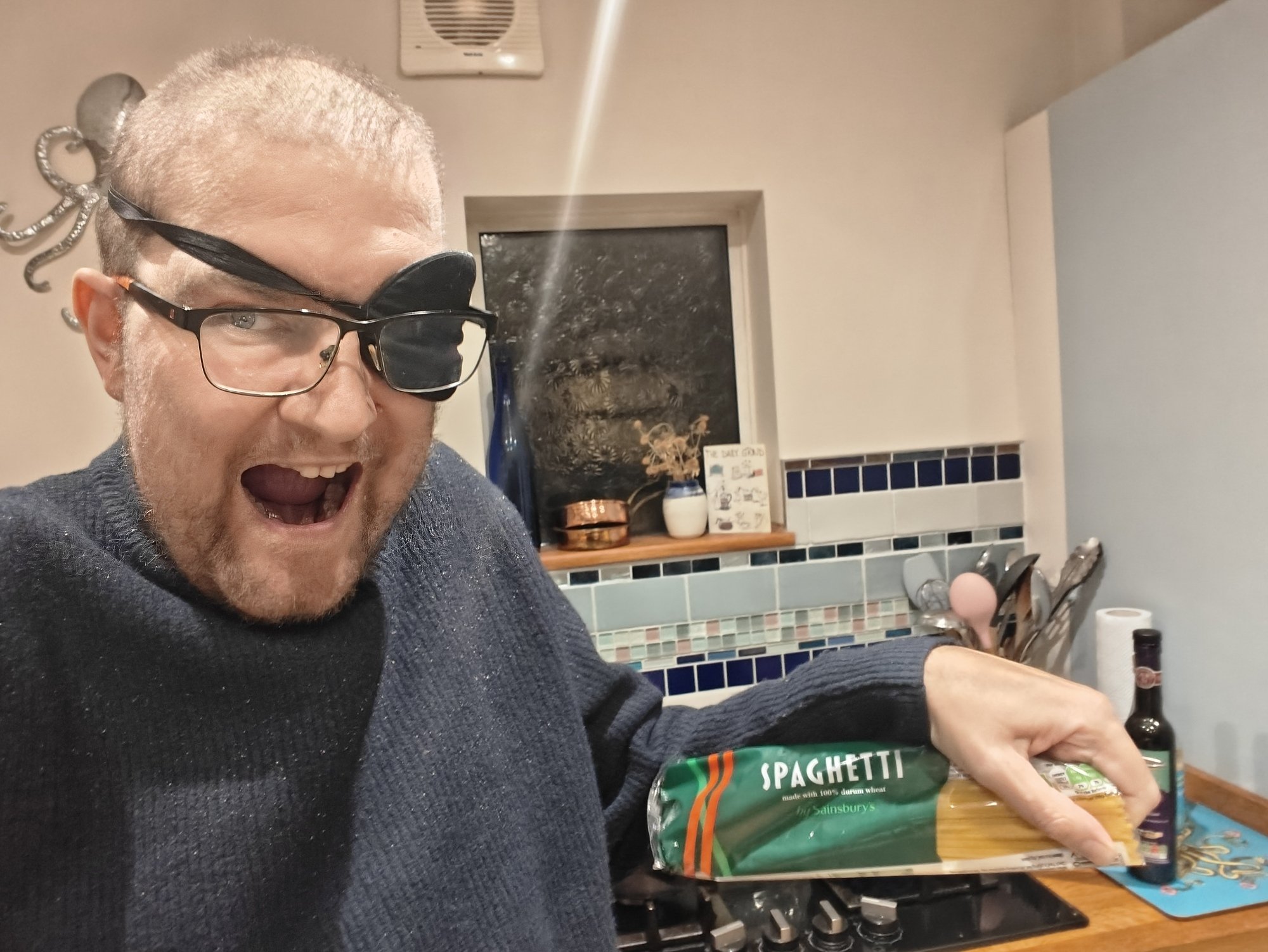 A picture of me holding a pack of spaghetti in an awkward way, wearing an eye patch
