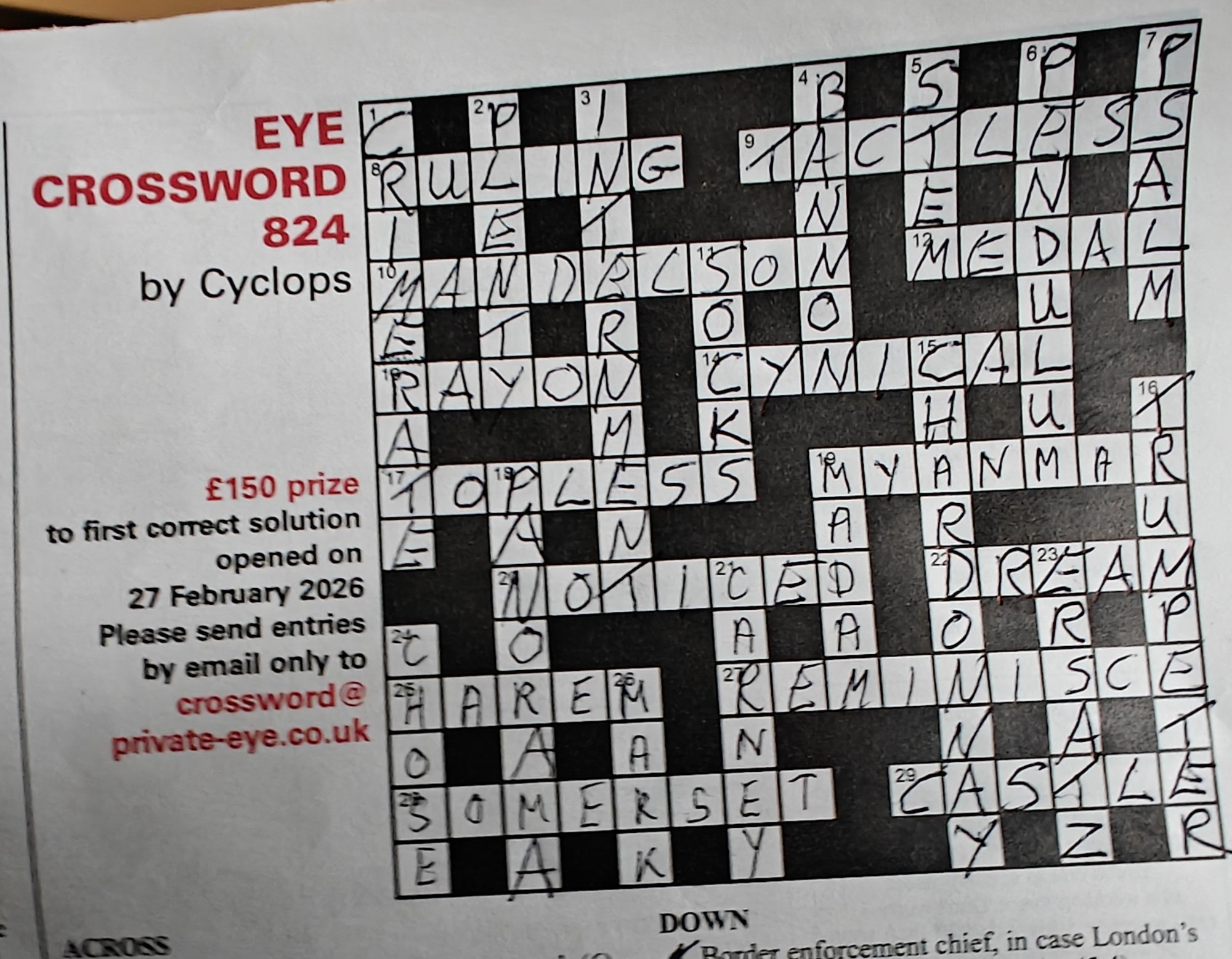 A photograph of a completed crossword puzzle titled “EYE CROSSWORD 824 by Cyclops,” printed on a white page. On the left, red text reads “EYE CROSSWORD 824” with “by Cyclops” in black underneath. Below that, smaller text advertises a £150 prize “to first correct solution opened on 27 February 2026” and asks for entries to be emailed to “crossword@private-eye.co.uk.”
On the right is the crossword grid, filled in by hand in black ink. Many answers are clearly legible, including: “RULING,” “MANDELSON,” “RAYON,” “TOPLESS,” “NOTICED,” “HAREM,” “SOMERSET,” “TACTLESS,” “BAN,” “MEDAL,” “CYNICAL”, “MYANMAR,” “DREAM,” “REMINISCE”, and “CASTLE.” Several intersecting vertical words are also completed, including “PENDULUM” and “TRUMPETER.” The handwriting is large and slightly uneven, filling most of the squares. The bottom of the image shows the heading “DOWN,” indicating the start of the down clues section.