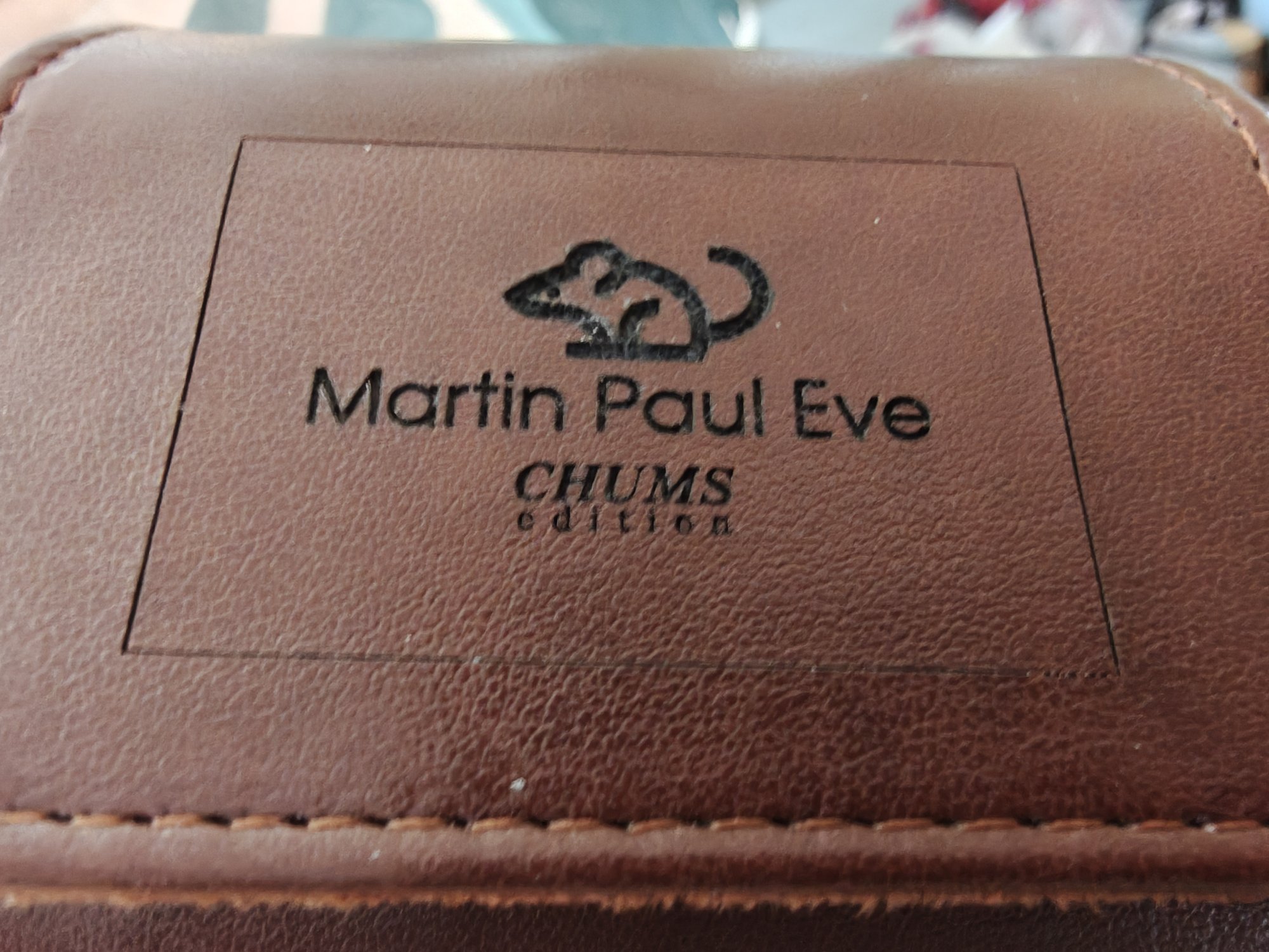 A picture of a leather watch case with an image of a mouse at the top, then the text Martin Paul Eve, then the text CHUMS EDITION 