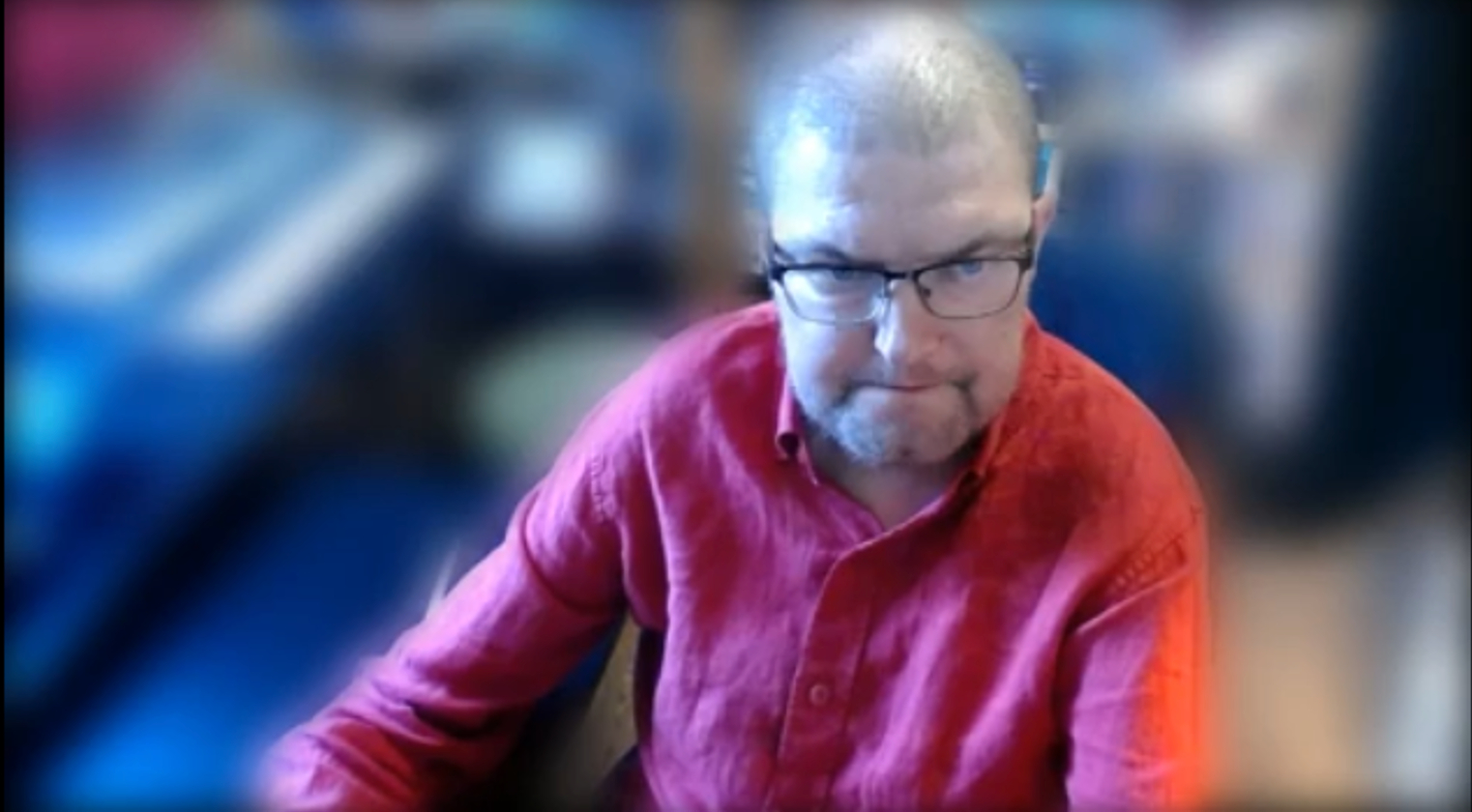 A picture of me in a red shirt, looking very serious and bordering on angry!