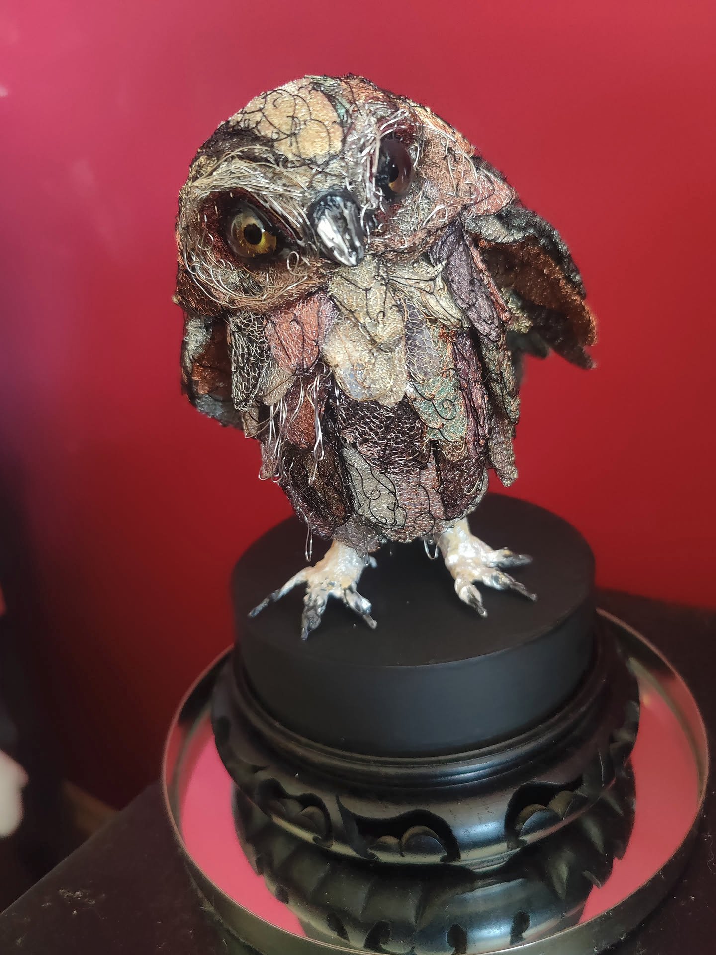 A sculpture of a little owl with its head tilted to the right. It is standing on a plinth. I am not sure what it is made of.